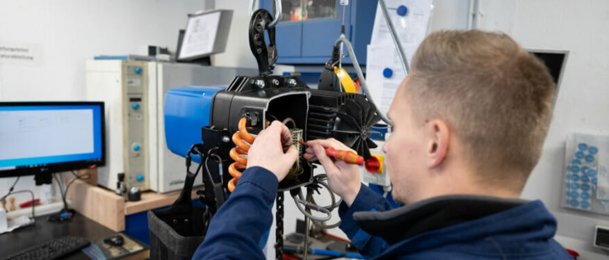 Techniker wartet einen Elektrokettenzug in einer Werkstatt.